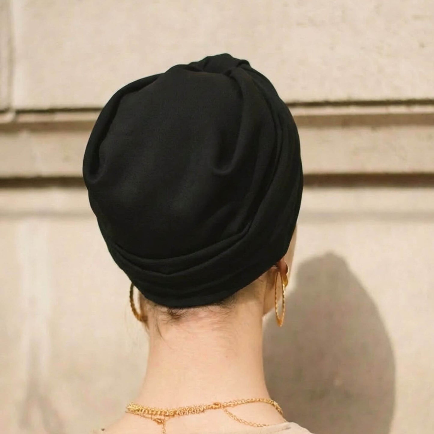 Mujer mostrando la parte trasera del turbante negro, ajustado cómodamente, con buen soporte y cobertura completa de la cabeza.