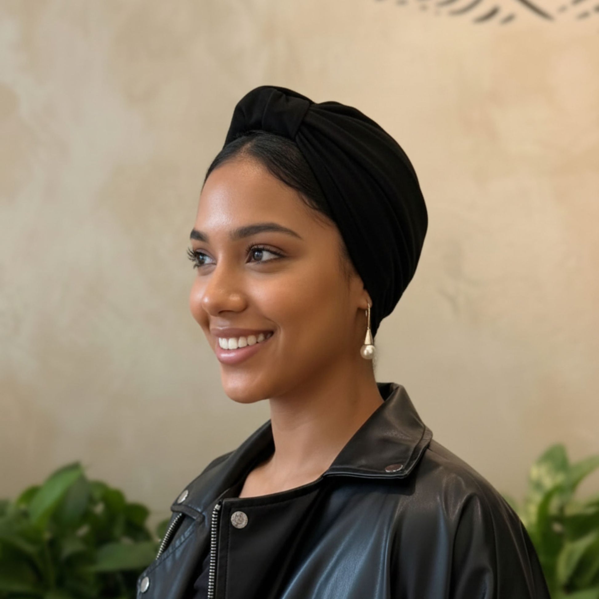 Mujer con turbante de algodón negro visto de perfil, estilo parisino sofisticado que aporta un toque elegante y natural.