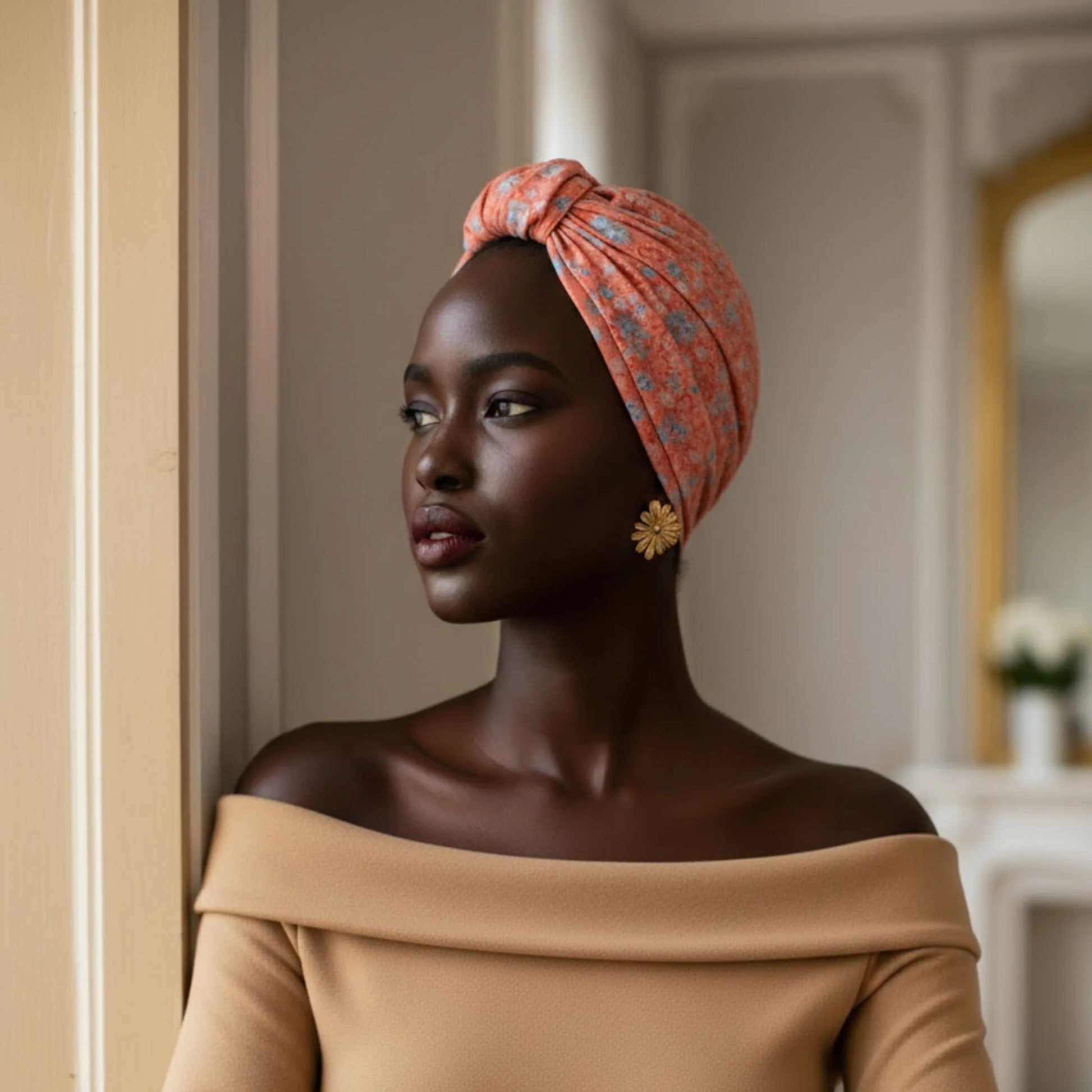 Mujer llevando un turbante Parisino Coral con diseño floral visto de perfil en interior