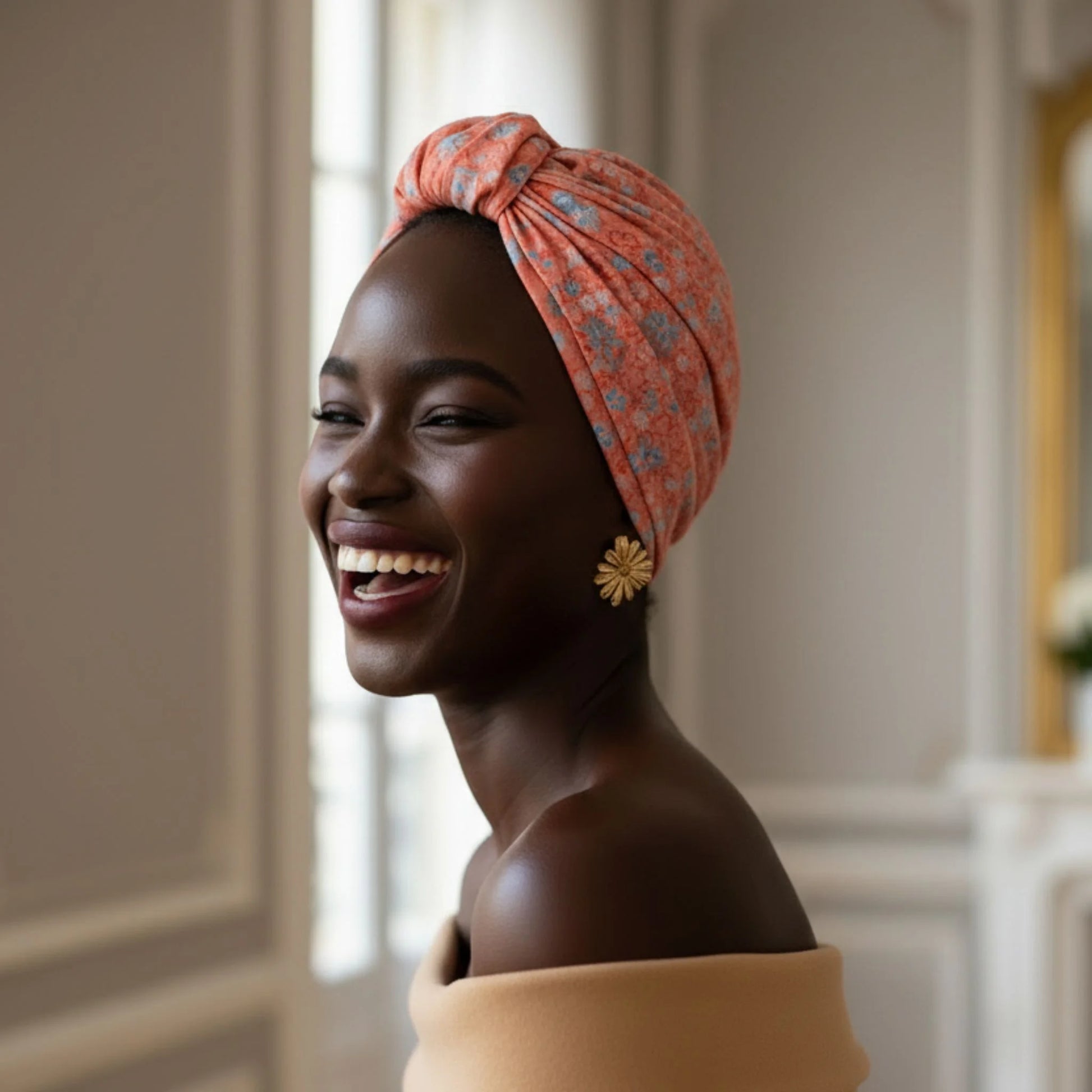 Mujer sonriendo con turbante Parisino Coral de estampado floral en un espacio interior
