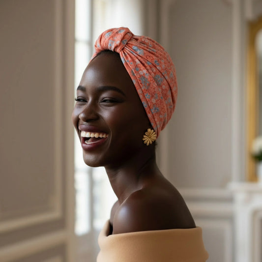 Mujer sonriendo con turbante Parisino Coral de estampado floral en un espacio interior