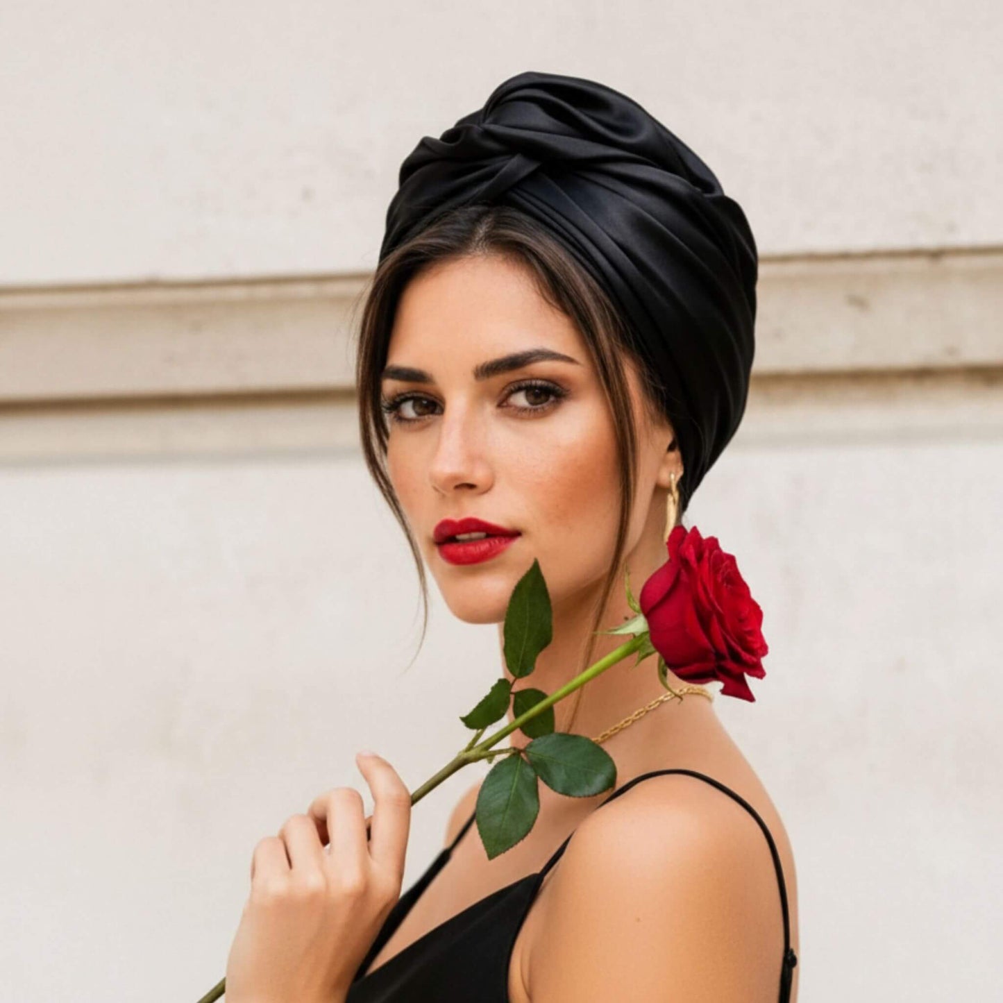 Mujer con turbante de satén negro visto de perfil, destacando la forma y el volumen del diseño con inspiración cubana.